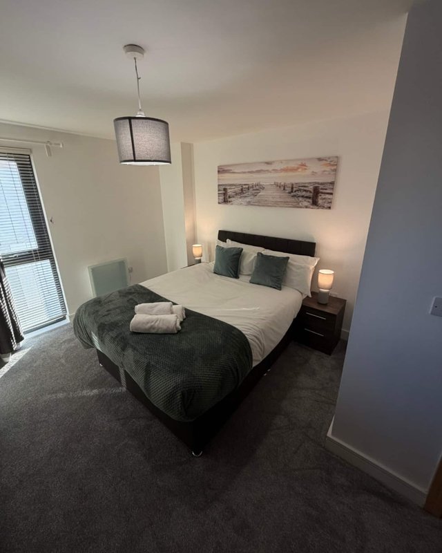 Modern bedroom with double bed, dark carpet, pendant lamp, and wall art