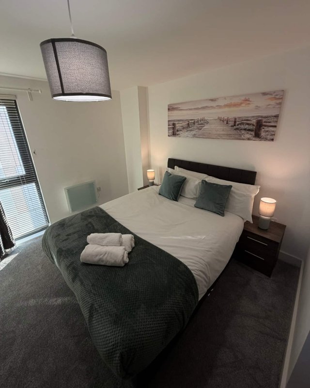 Modern bedroom with double bed, rolled towels, pendant light, and wall art