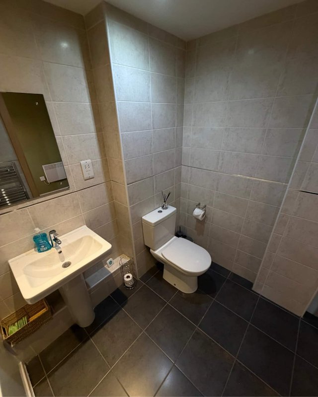 Modern bathroom with sink, toilet, mirror and tiled walls and floor