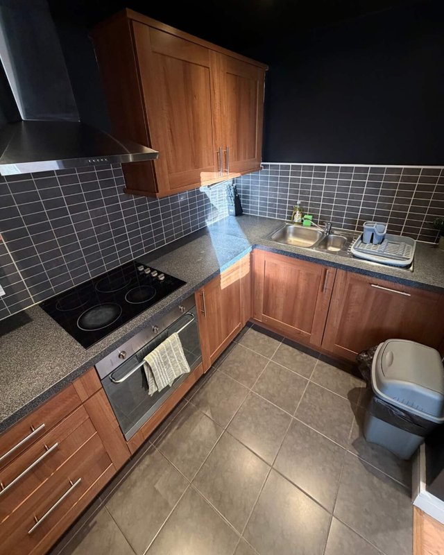 Kitchen with wooden cabinets, black tile backsplash, induction hob and built-in oven