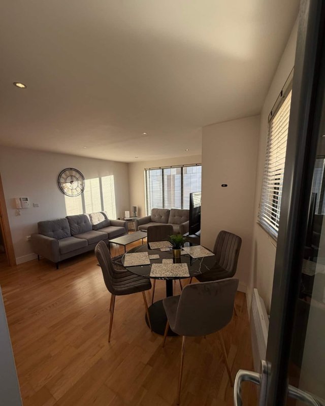 Open-plan living and dining area with sofa, dining table, chairs, and large windows