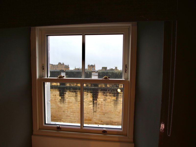 Window with wooden frame overlooking cityscape with historic stone buildings