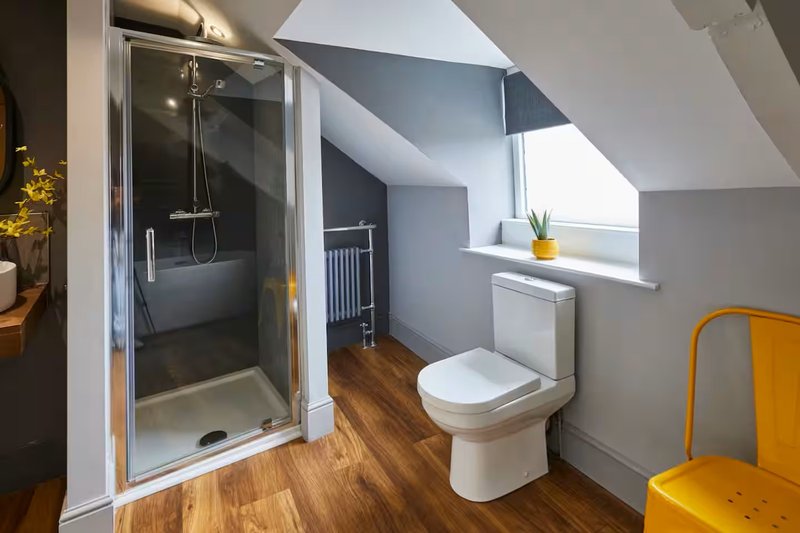 Modern bathroom with shower enclosure, toilet, wooden flooring and skylight window