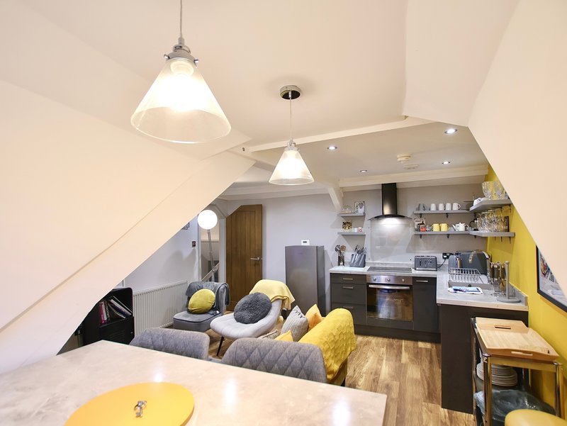 Bright loft studio with kitchenette, seating area, pendant lights and yellow accents