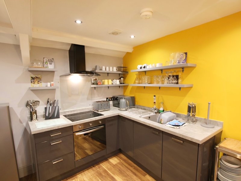 Modern kitchen with dark cabinetry, white countertops, yellow accent wall and open shelving