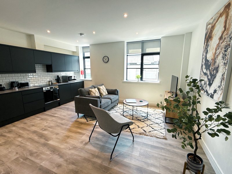Open-plan apartment with modern kitchen, seating area, wooden flooring and large windows