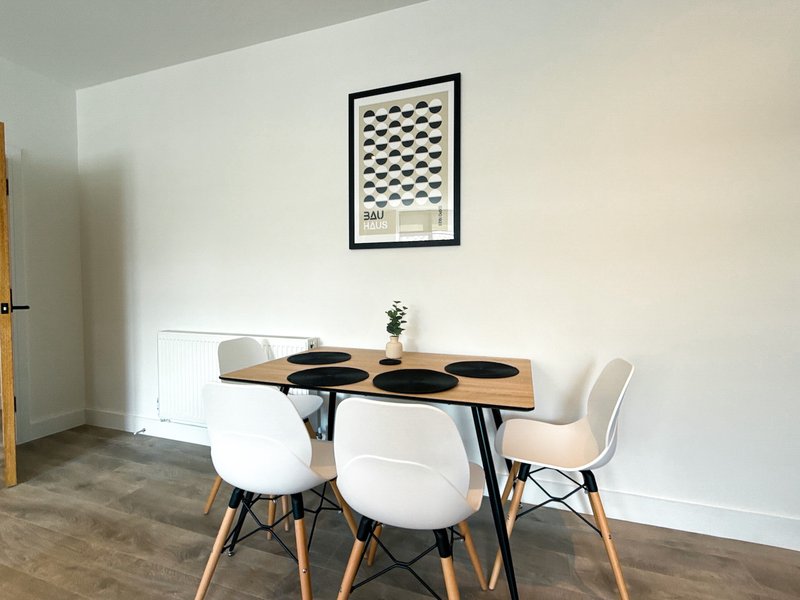 Modern dining area with wooden table, white chairs, and geometric wall art