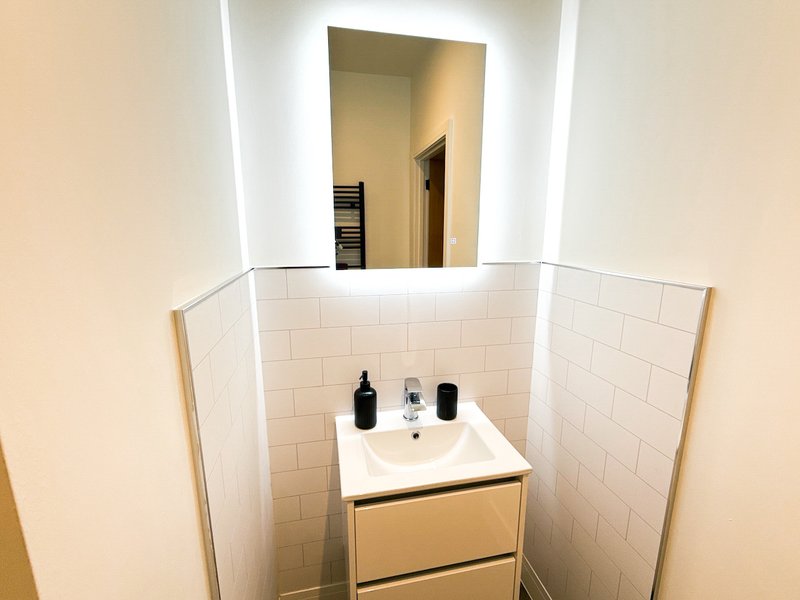 Modern bathroom with white subway tiles, vanity sink, mirror, and bathroom products
