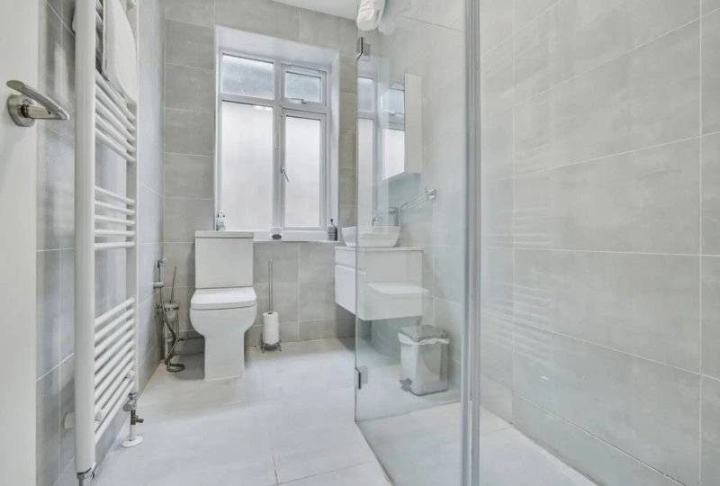 Modern bathroom with white tile walls, toilet, sink, shower enclosure and heated towel rail