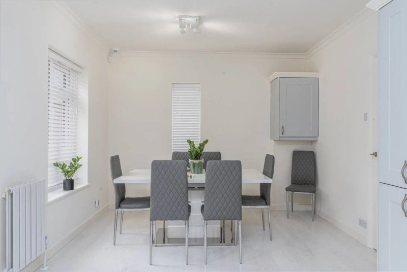 Modern dining room with round table, grey chairs, potted plants and window blinds