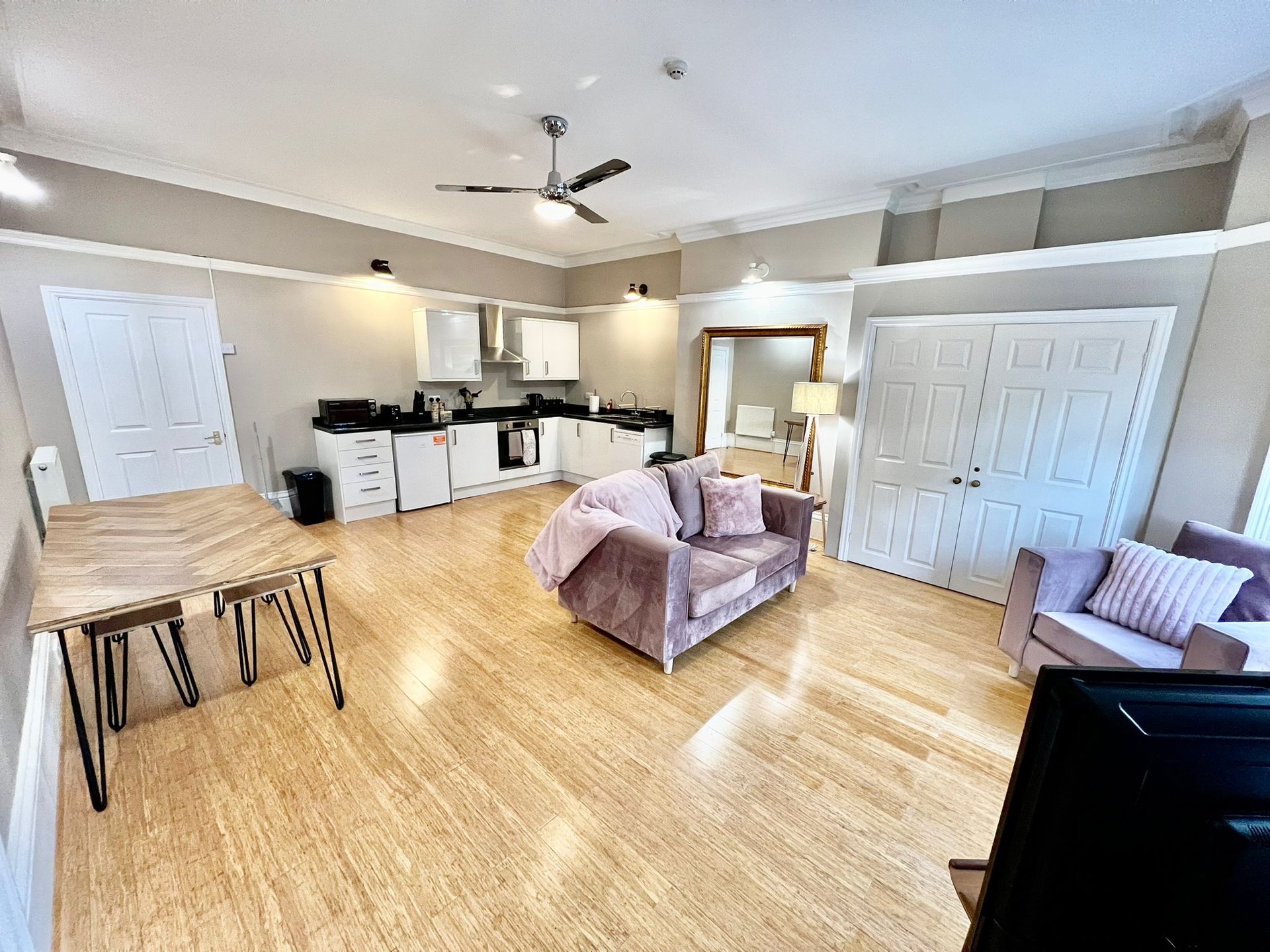 Open-plan living space with kitchen, dining area, and seating with wooden flooring