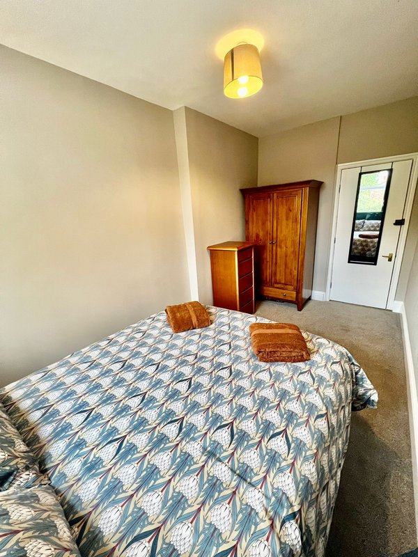 Bedroom with double bed, wooden furniture, ceiling light and door to outside