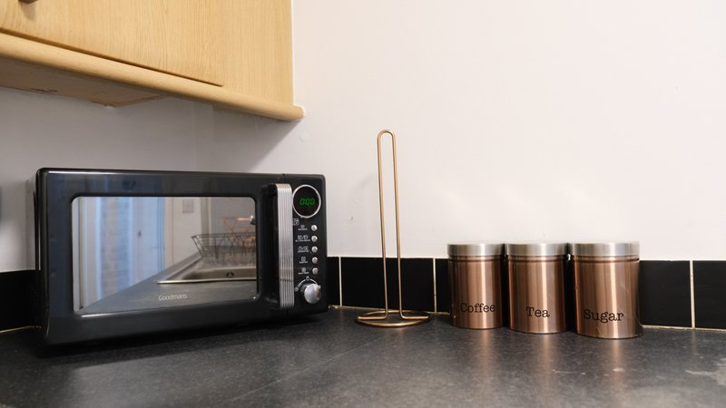 Kitchen counter with black microwave, copper canisters, and utensil holder
