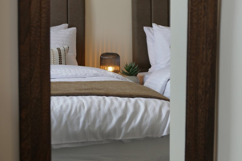 Bedroom with double bed, white bedding, brown headboard and curtains, bedside decor