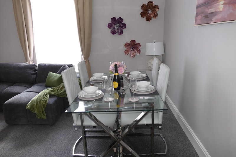 Dining table set for two with wine bottle, flowers, and place settings in open-plan living space