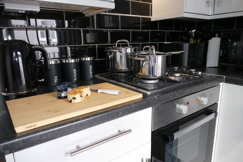 Modern kitchen with black subway tiles, white cabinetry, dark countertop, and stainless steel appliances