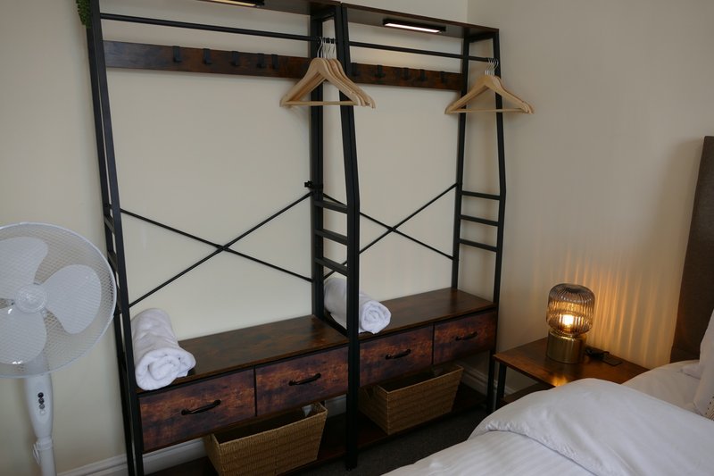 Industrial-style bedroom with black metal frame bed, white bedding, wooden drawers, and warm lighting