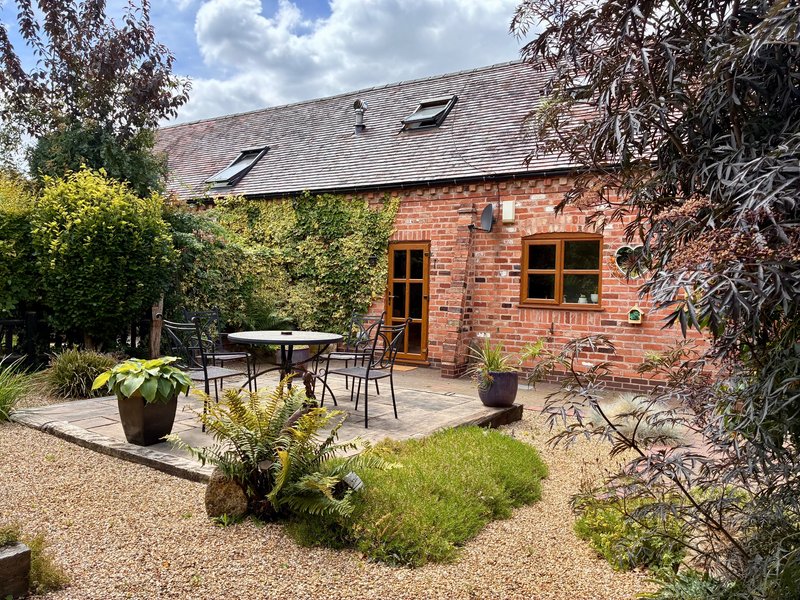 Brick cottage exterior with patio, outdoor seating area, and landscaped garden