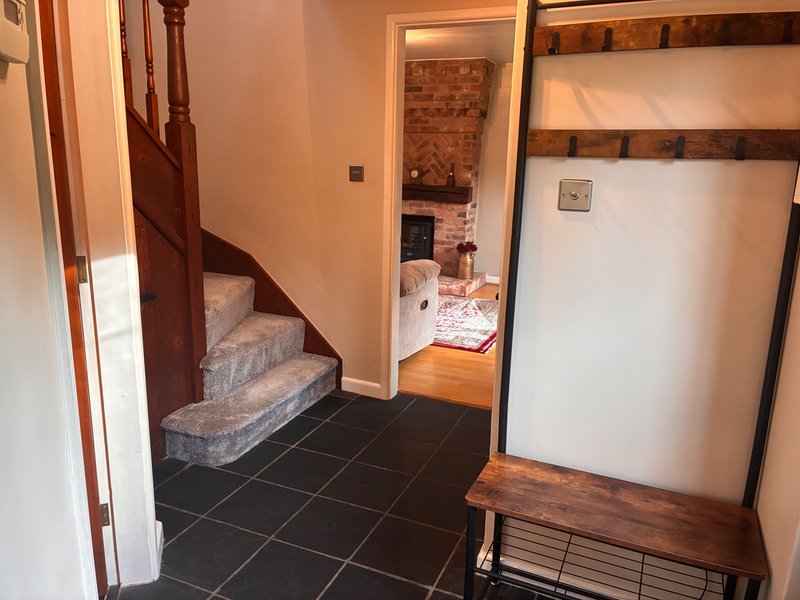 Hallway with staircase, wooden furniture, black tile floor, and doorways to adjacent rooms
