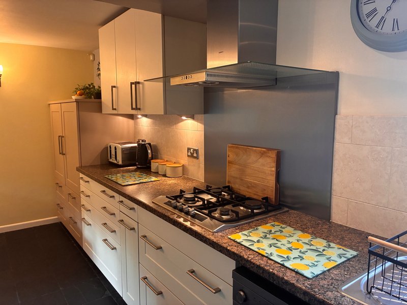Modern kitchen with white cabinets, granite countertop, gas hob and stainless steel range hood