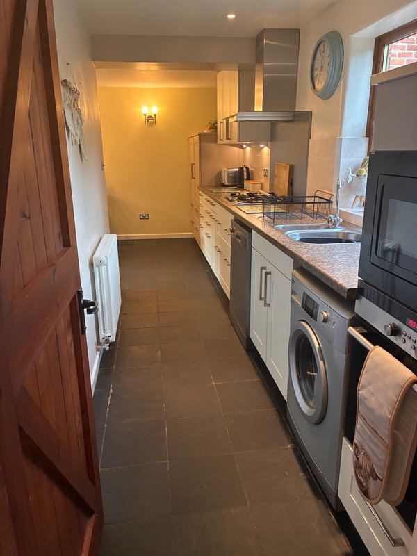 Galley kitchen with gas cooktop, washing machine, and cream cabinetry