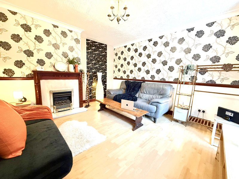 Living room with fireplace, patterned wallpaper, blue sofa, and light wood flooring