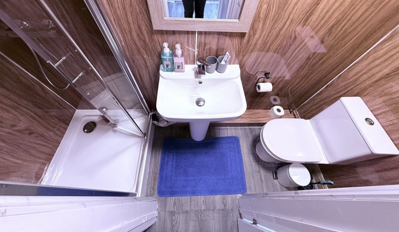 Compact bathroom with pedestal sink, toilet, shower enclosure and blue mat