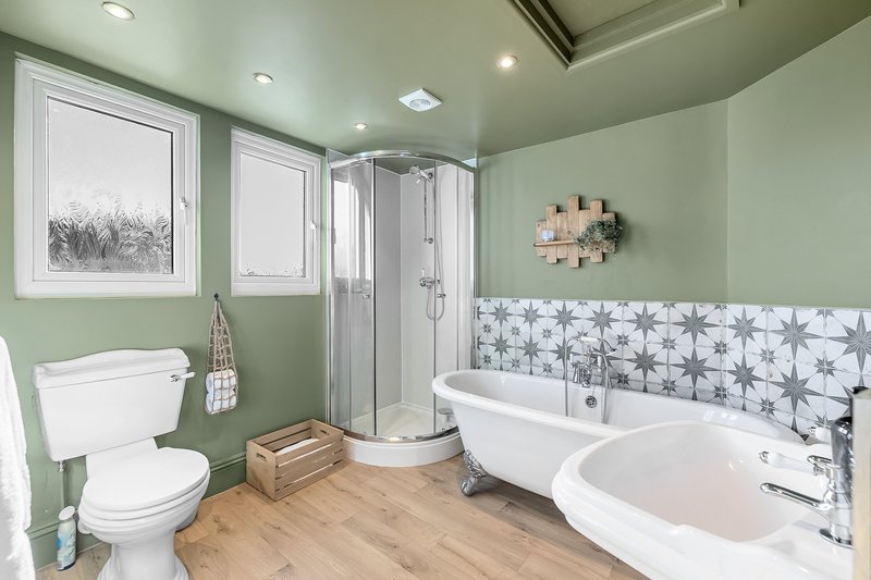 Spacious bathroom with dual freestanding tubs, shower enclosure, toilet and wooden flooring