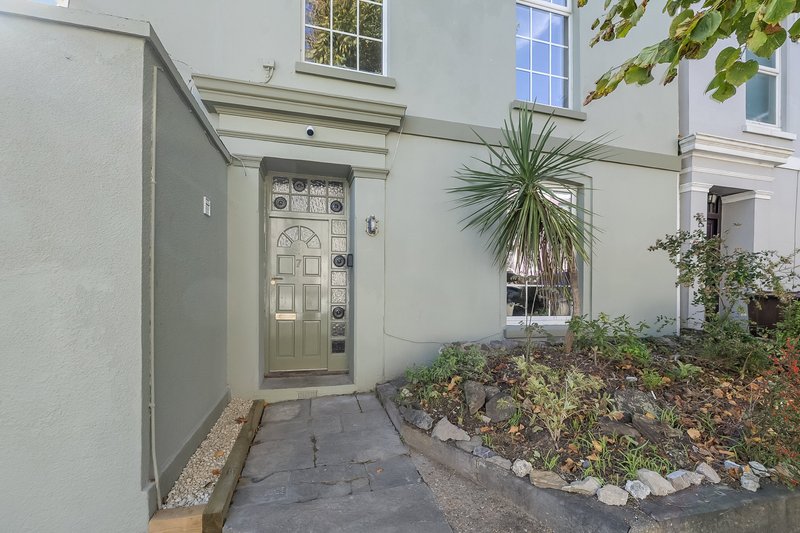 Property entrance with pale green door, window, plants and gravel pathway