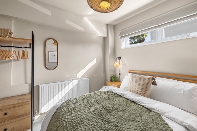 Bright modern bedroom with double bed, wooden floor, radiator and skylight window