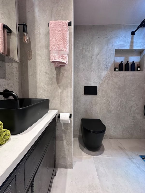 Modern bathroom with black sink, pink towel, black toilet and walk-in shower