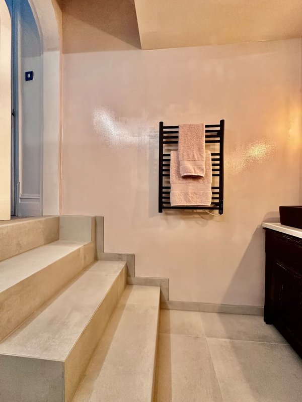 Modern bathroom with stepped wooden bench seating, wall-mounted towel rack and heated rails