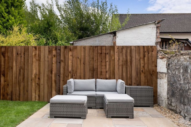Garden patio area with gray rattan furniture set and wooden fence backdrop