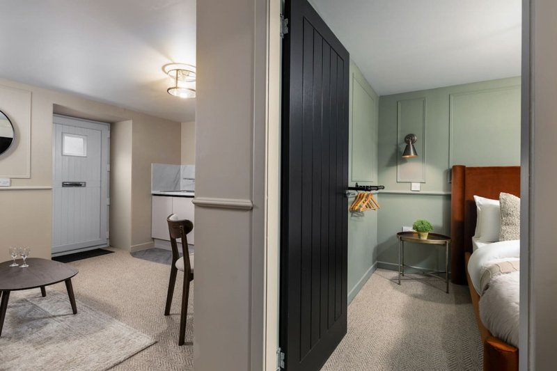 Interior hallway connecting living area to bedroom with wood door, neutral decor