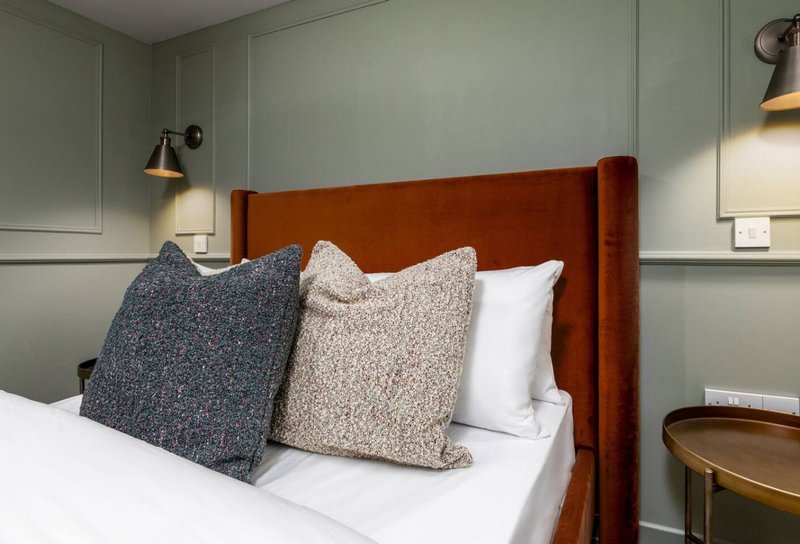 Modern bedroom with rust-colored upholstered headboard, white bedding, and decorative throw pillows
