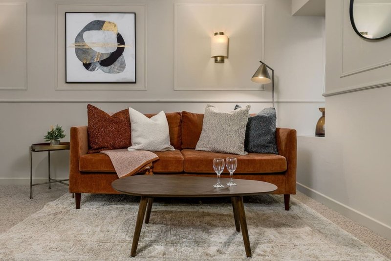 Modern living room with brown leather sofa, patterned cushions, wooden coffee table and wall art