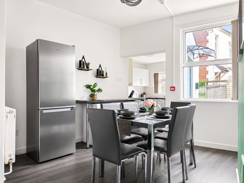 Modern kitchen-diner with stainless steel fridge, dining table, chairs and window view