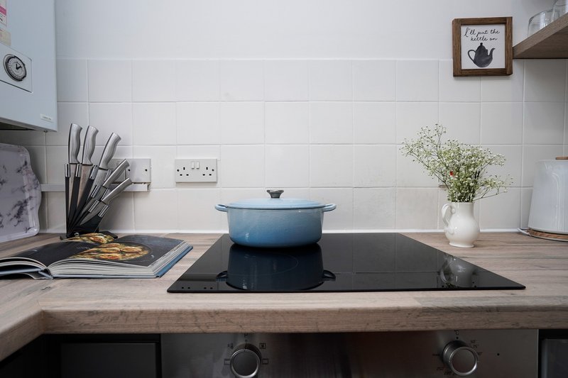 Modern kitchen with induction hob, blue cookware, and wooden countertop