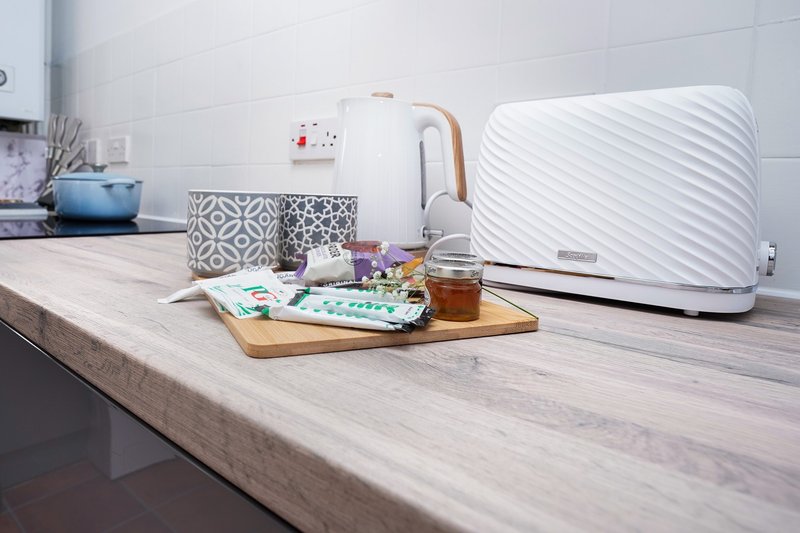 Modern kitchen counter with white toaster, wooden tray, decorative containers and kitchen accessories