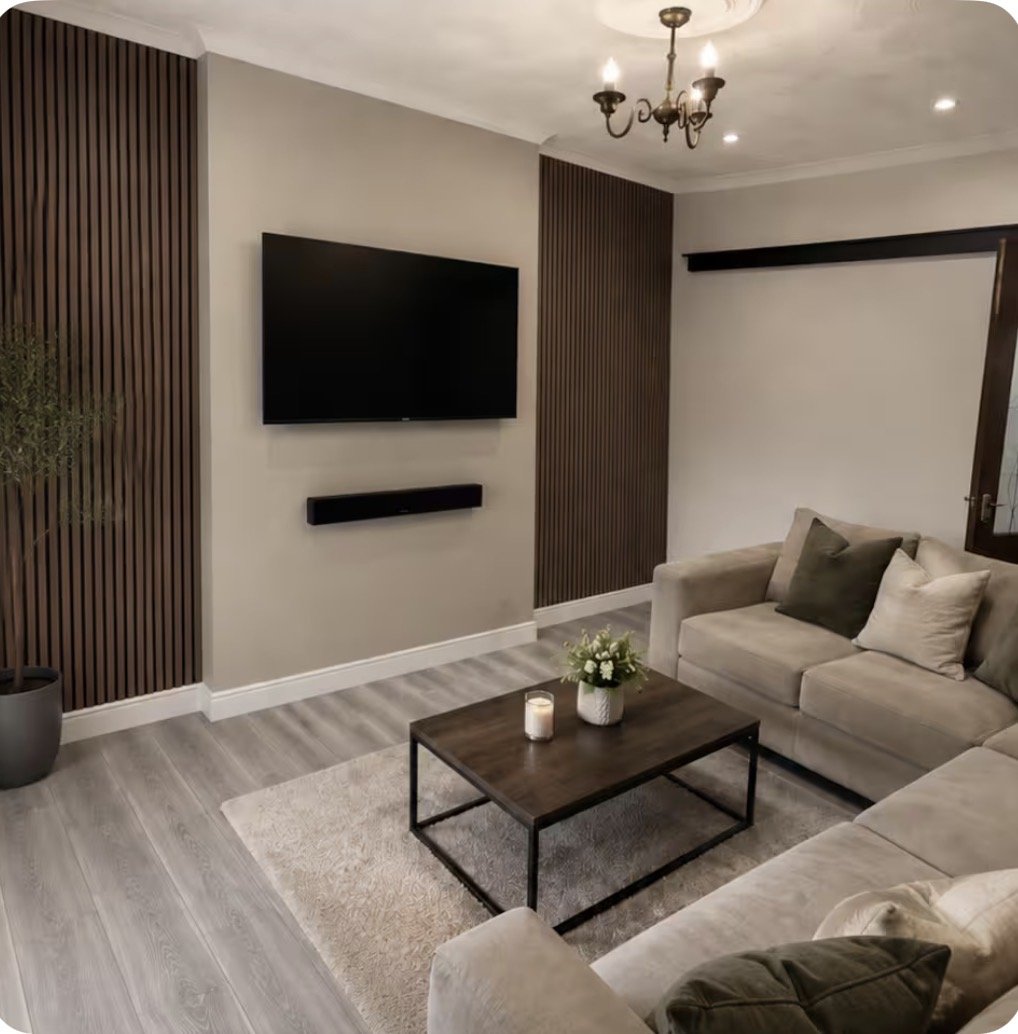 Modern living room with wall-mounted TV, cream sofa, wooden coffee table and pendant lighting
