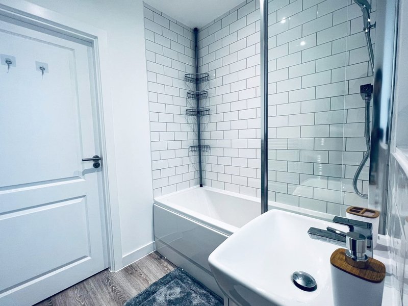 Modern bathroom with white subway tile walls, walk-in shower, white vanity sink and mirror