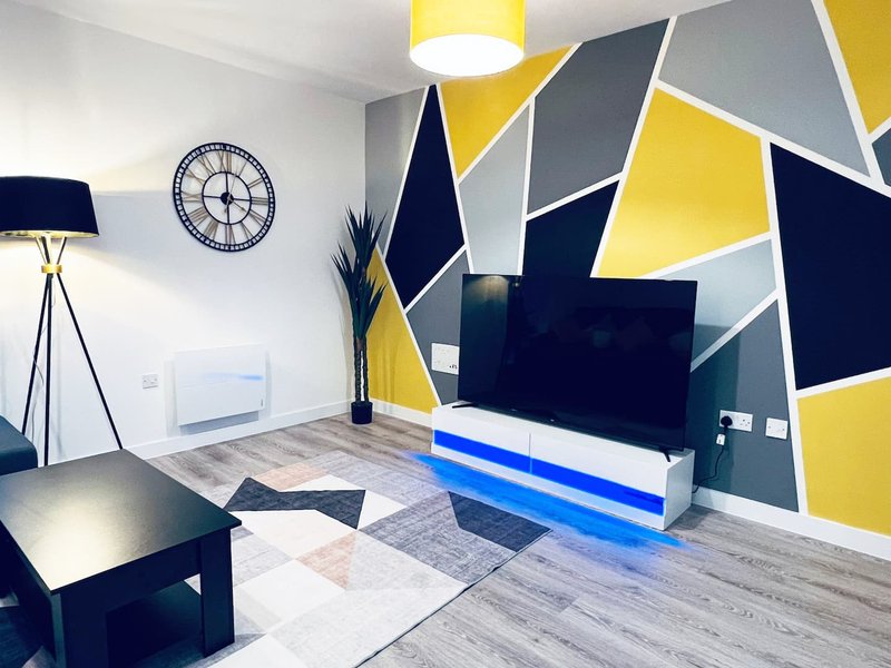 Modern living room with geometric wall art, flat-screen TV, floor lamp and round wall clock