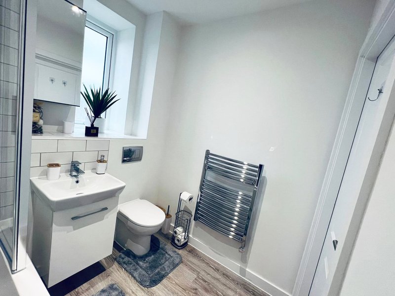Modern bathroom with white sink, toilet, heated towel rail and mirror above sink