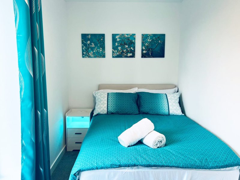 Bright bedroom with turquoise bedding, white pillows, coordinating wall art and curtains