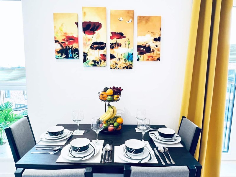 Dining room with black table set for four, modern artwork above, yellow curtains and city views