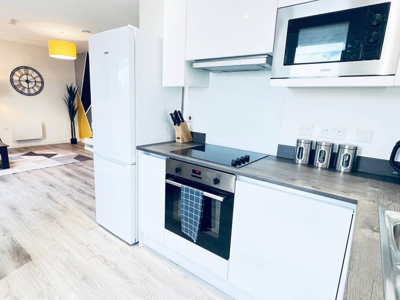 Modern kitchen with white cabinetry, built-in oven, microwave, and stainless steel countertop