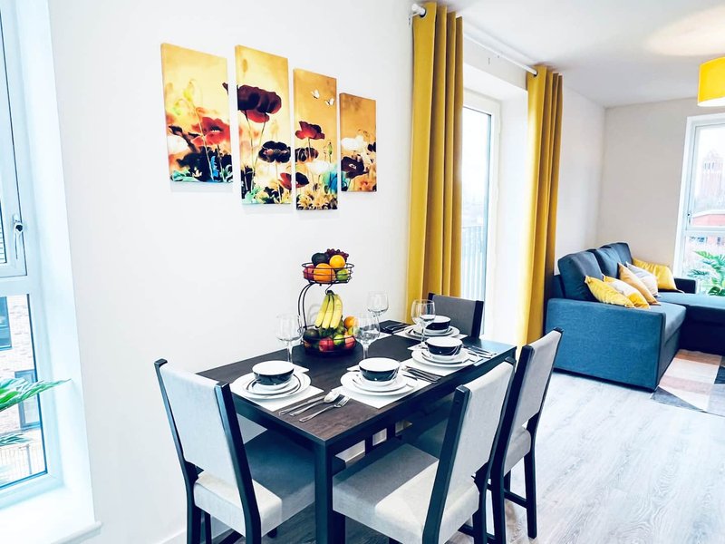 Modern open-plan living space with dining table set for four, blue sofa, and colorful wall art