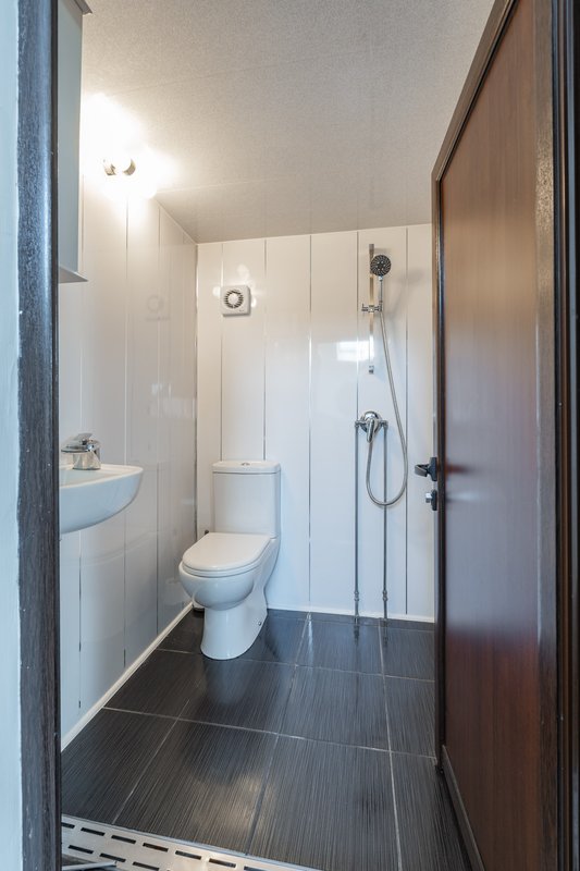 Modern bathroom with toilet, sink, shower cubicle and dark tile flooring