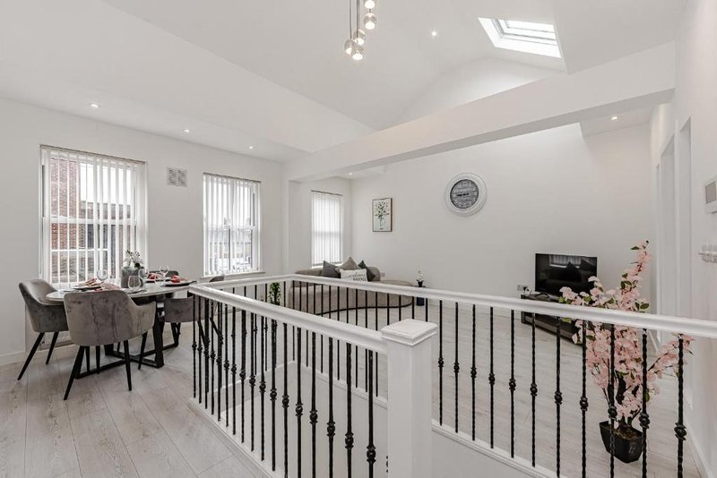 Modern open-plan landing with mezzanine railing, desk area, and natural skylights