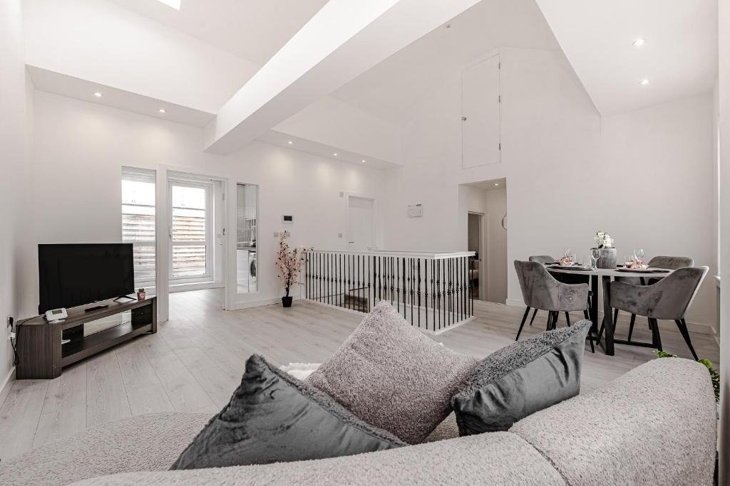 Open-plan living room with grey sofa, TV, dining table, and mezzanine level with railings
